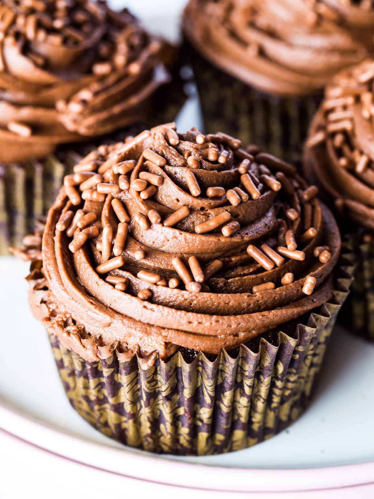 Gluten-free chocolate cupcakes with frosting on platter.
