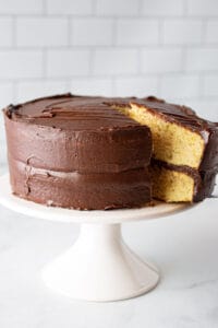 Almond flour yellow cake with chocolate frosting on cake stand.