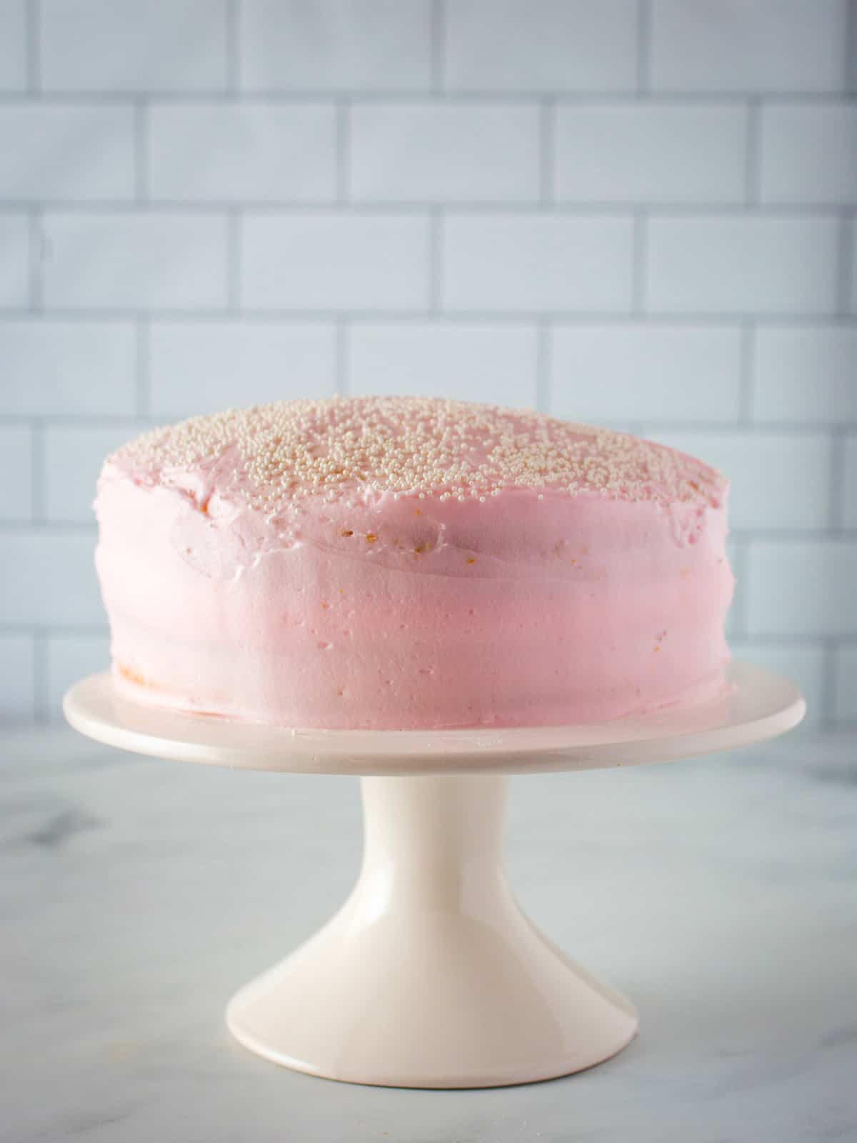 Almond flour cake with pink frosting on a cake stand.