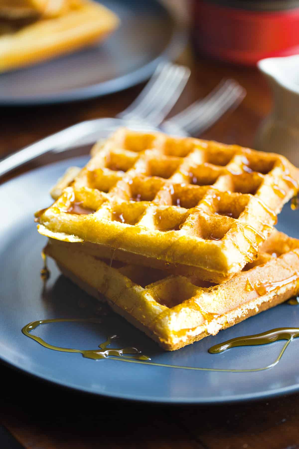 Two almond flour waffles on a plate with syrup.