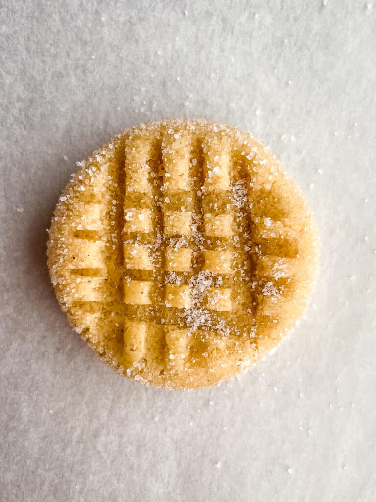 Gluten-free peanut butter cookie dough with crisscross fork pattern and granulated sugar.