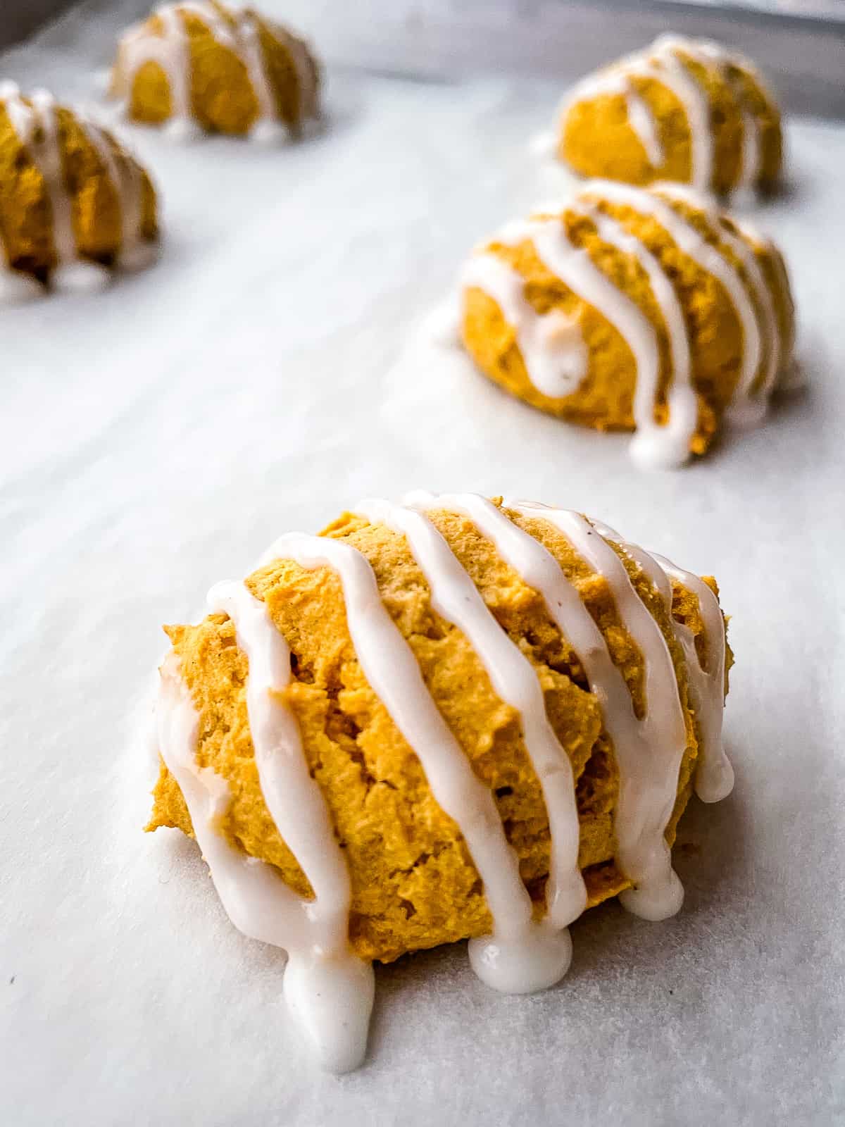 Gluten-free pumpkin cookies baked and iced on a baking sheet.