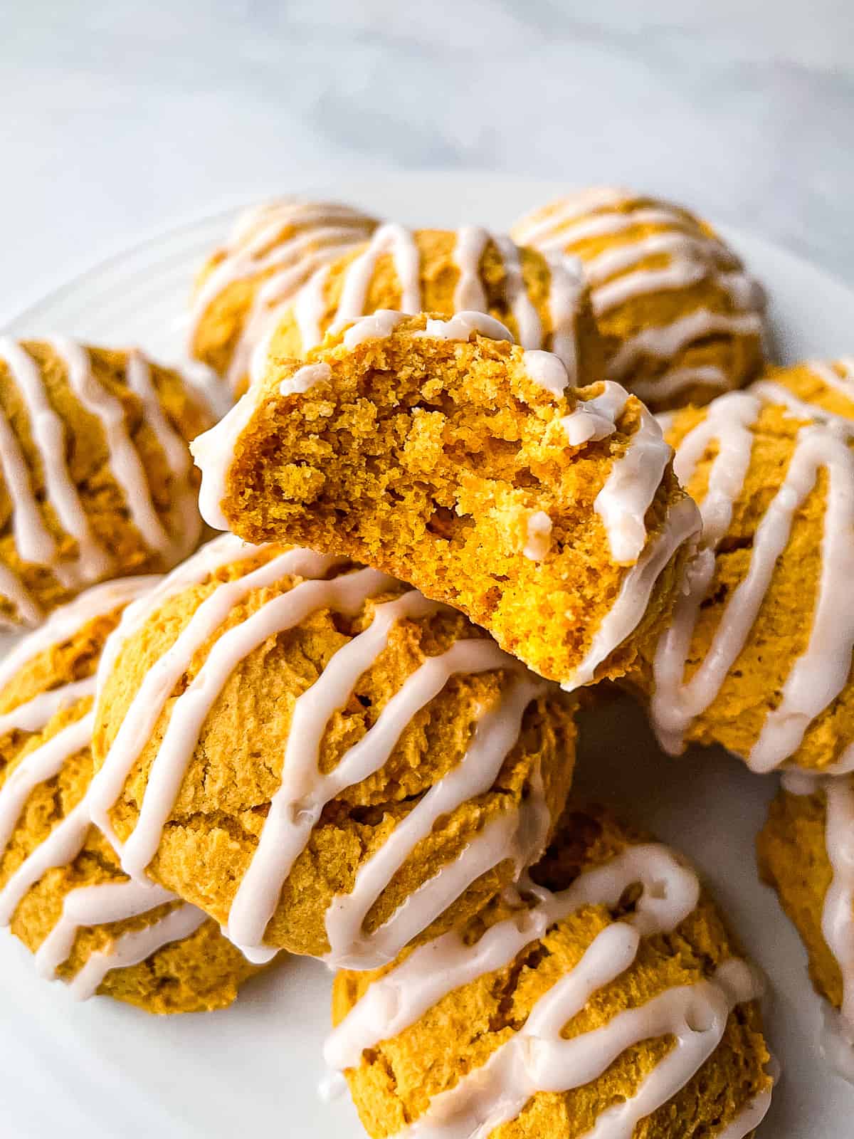 Gluten-free pumpkin cookies on a plate. One is cut in half to show texture.