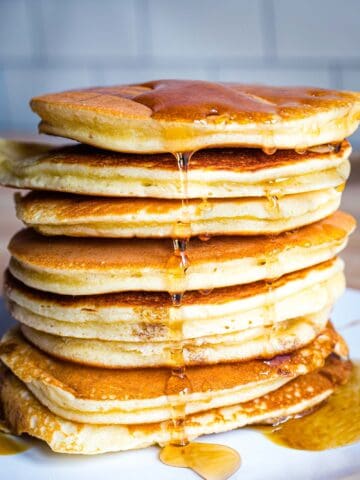 Stack of eight almond flour pancakes with maple syrup.