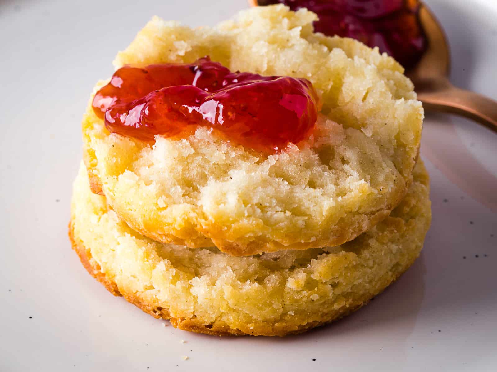 Gluten-free biscuit split in half with a dollop of jam on top.