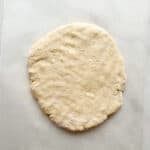 Gluten-free scone dough pressed out on a piece of parchment.