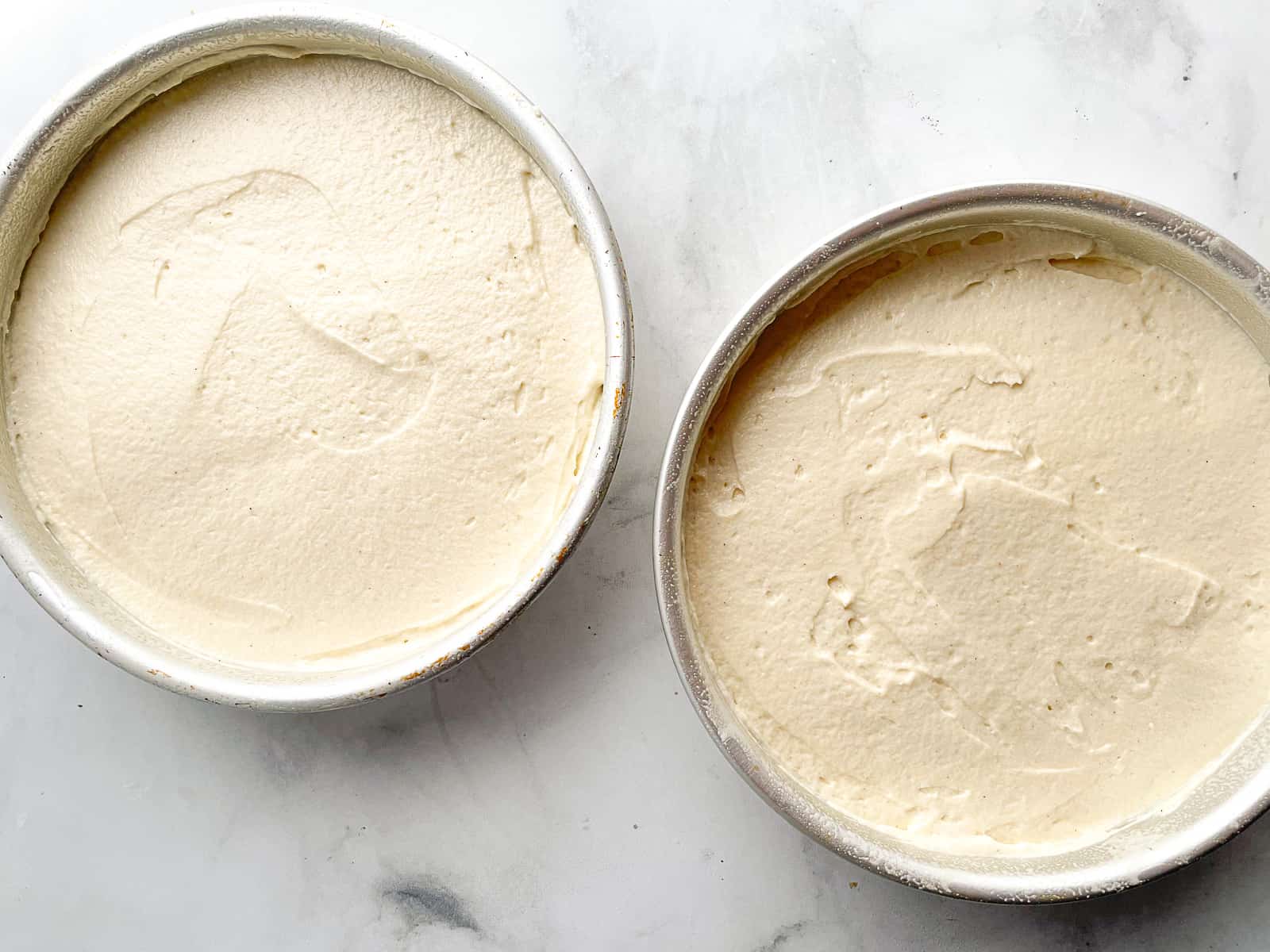 Gluten-free vanilla cake batter in two round cake pans.