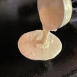 Ladling gluten-free pancake batter onto a griddle.