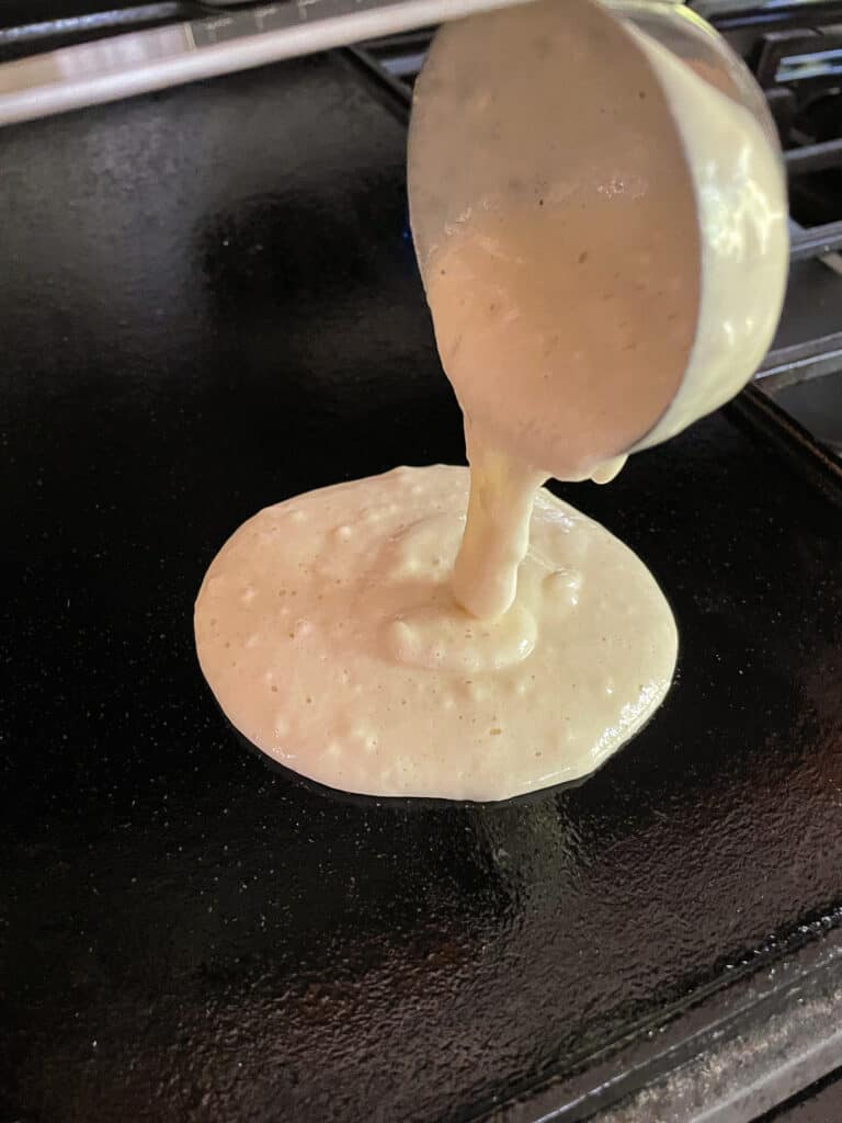 Ladling gluten-free pancake batter onto a griddle.