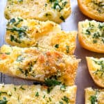 Slices of baked gluten-free garlic bread on a sheet pan.