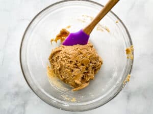 Gluten-free zucchini bread batter right after mixing. Very thick with a purple spatula in the bowl.
