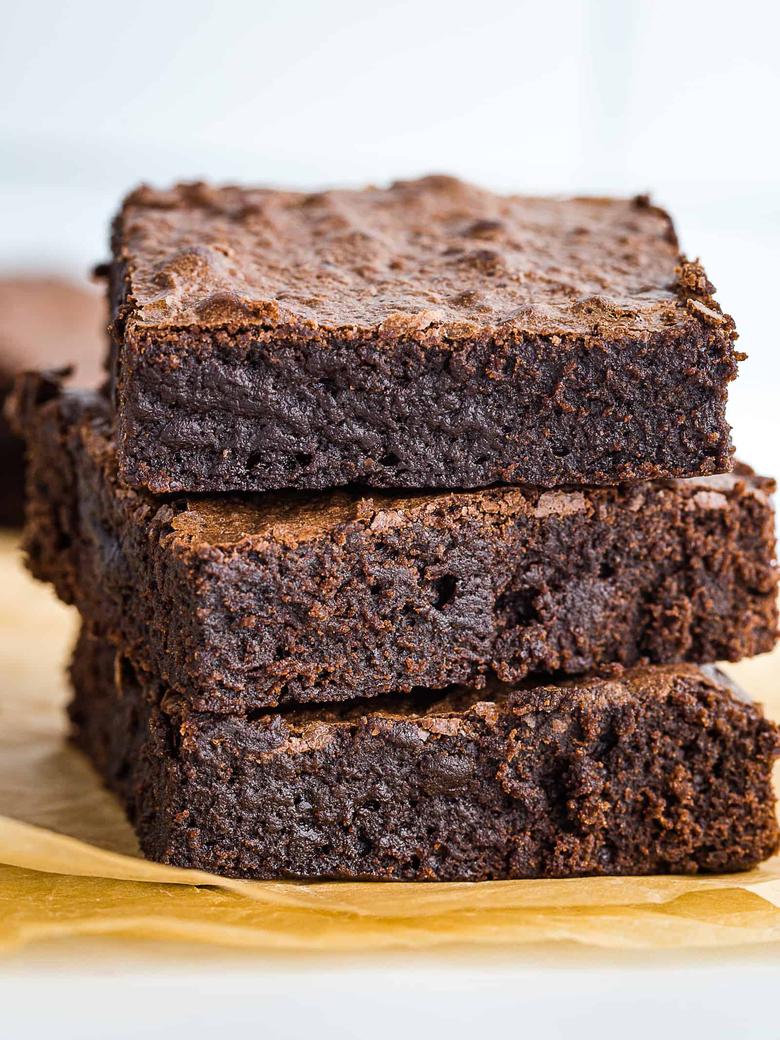 Stack of gluten-free brownies on a brown piece of parchment paper.