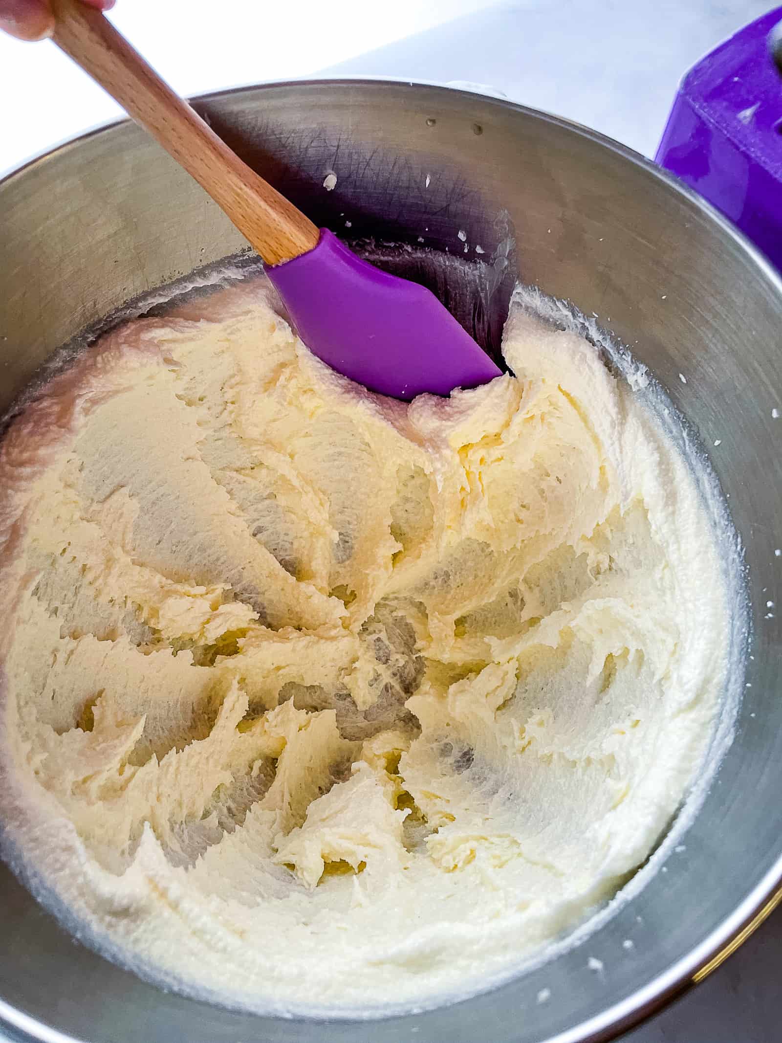 Scraping butter from the side of a mixing bowl.