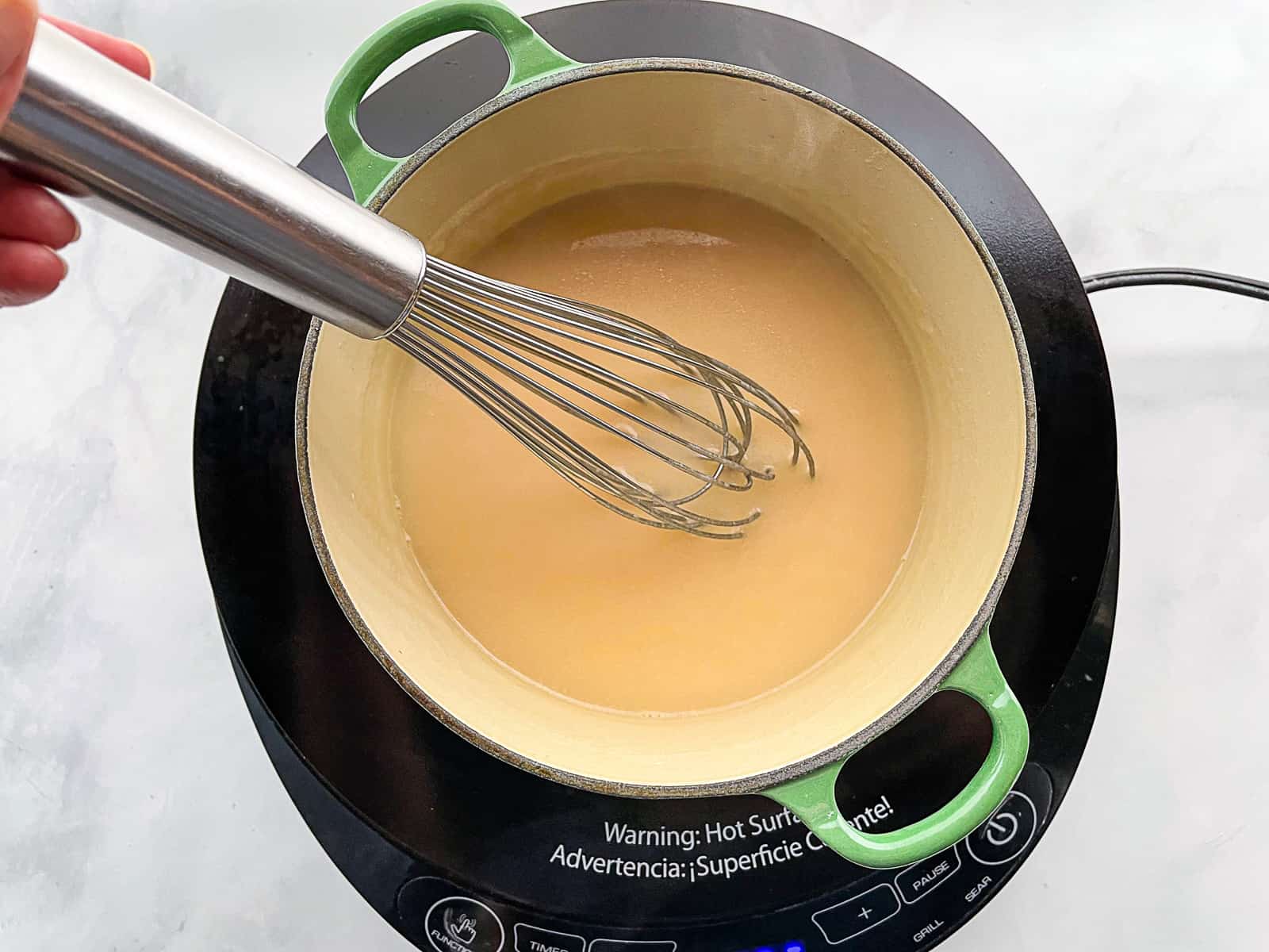 Gluten-free gravy being whisked in a pan.