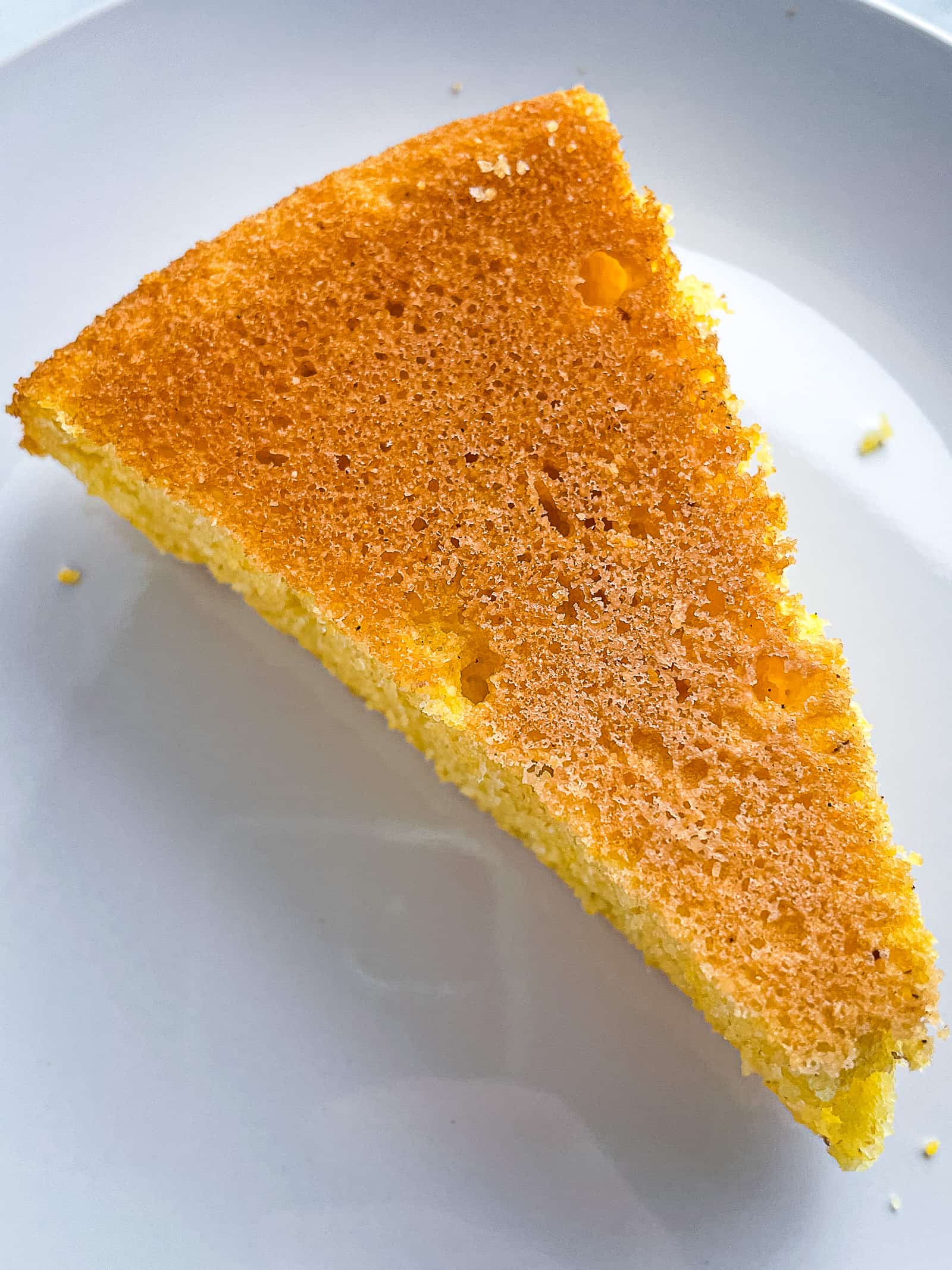 Bottom of a slice of gluten-free cornbread. It's evenly golden brown.