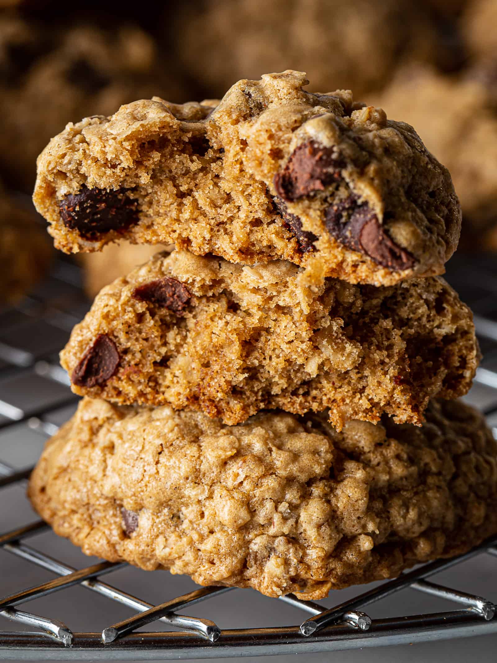A stack of three gluten-free oatmeal cookies. The top two cookies are broken in half to show the chocolate chips insides.