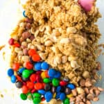 Mxing M&Ms, peanuts, and butterscotch chips into gluten-free monster cookie dough.