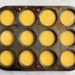 Gluten-free corn muffin batter in an old, greased muffin pan.