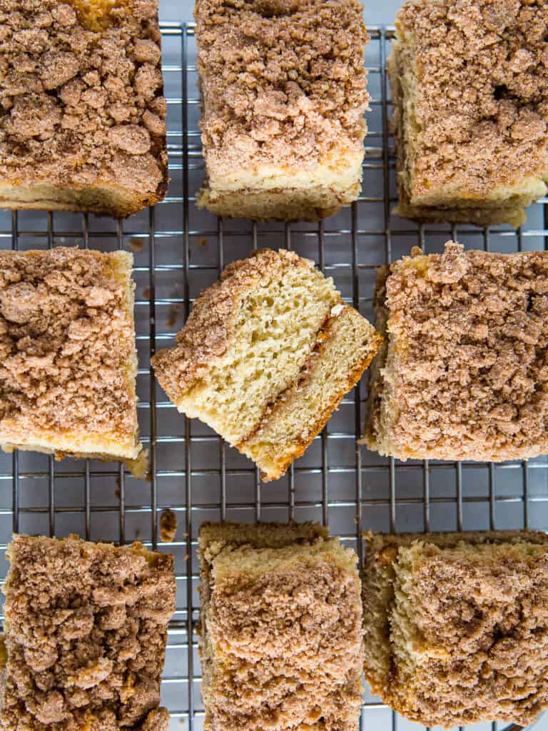 Gluten-free coffee cake slices on a cooling rack. The slice in the middle is turned on its side to show the layer of cinnamon-sugar filling.