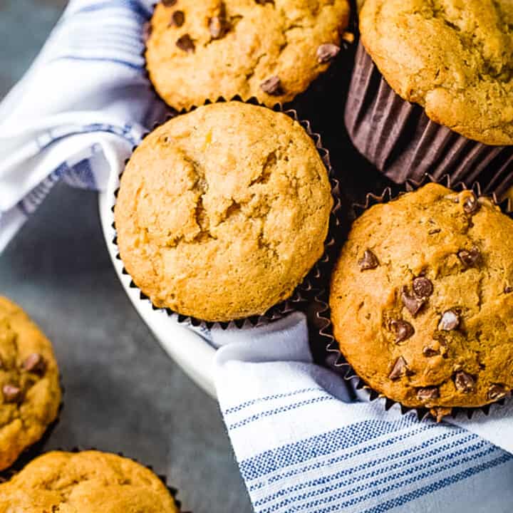 Gluten-Free banana muffins in a towel-lined bowl. Some of the muffins have chocolate chips.