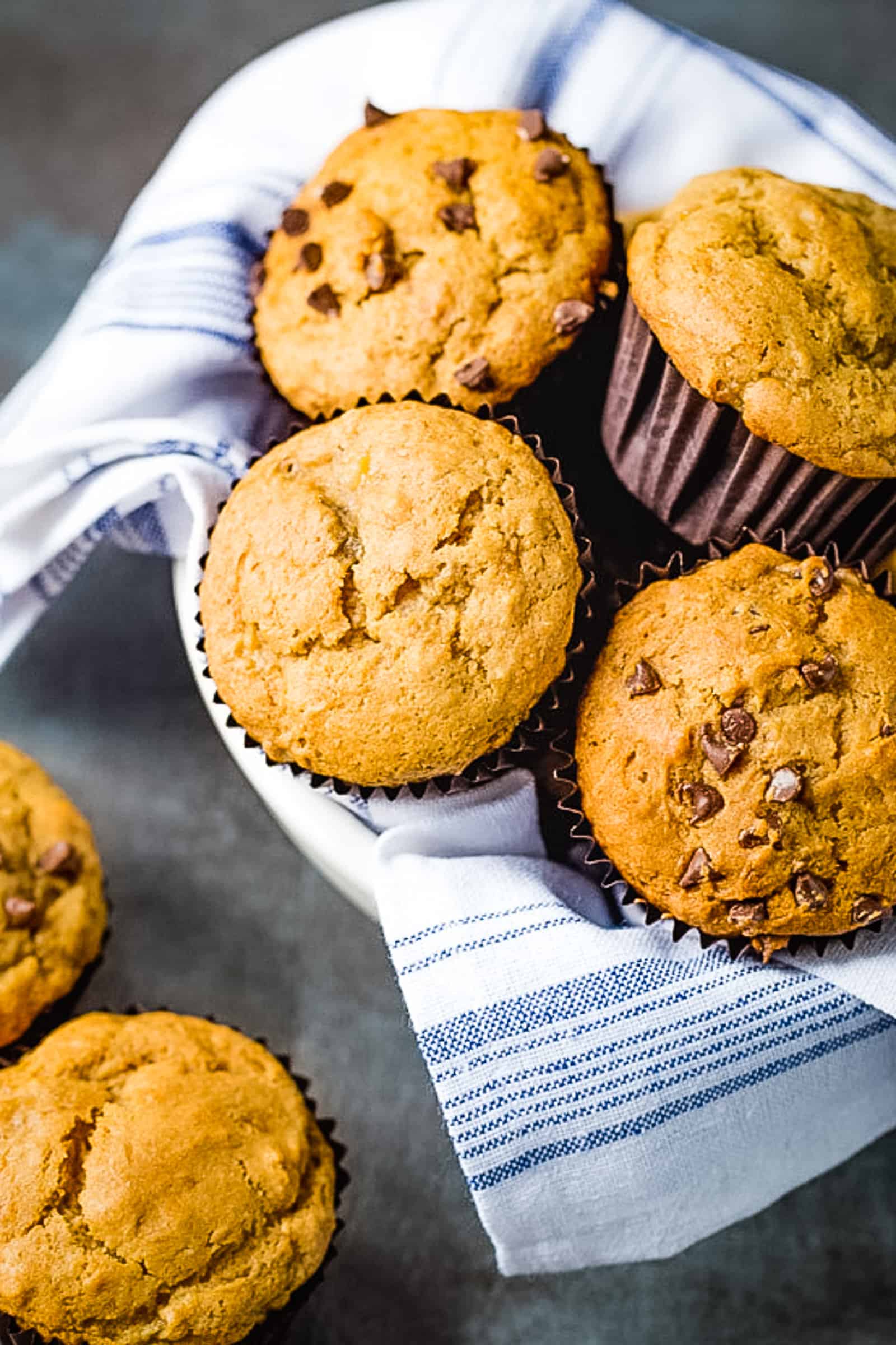 Gluten-Free banana muffins in a towel-lined bowl. Some of the muffins have chocolate chips.
