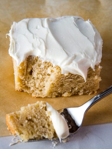 Slice of gluten-free banana cake frosted with cream cheese frosting.