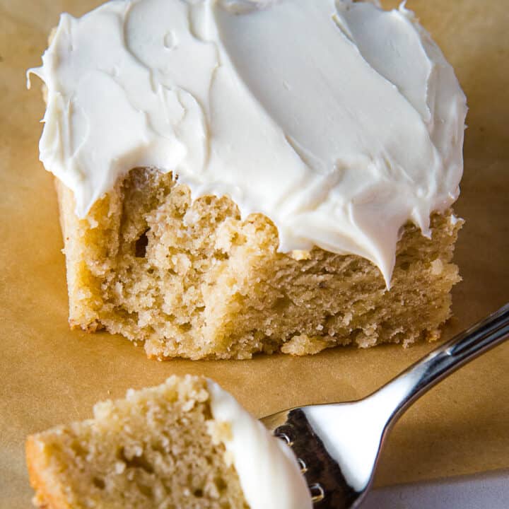 Slice of gluten-free banana cake frosted with cream cheese frosting.