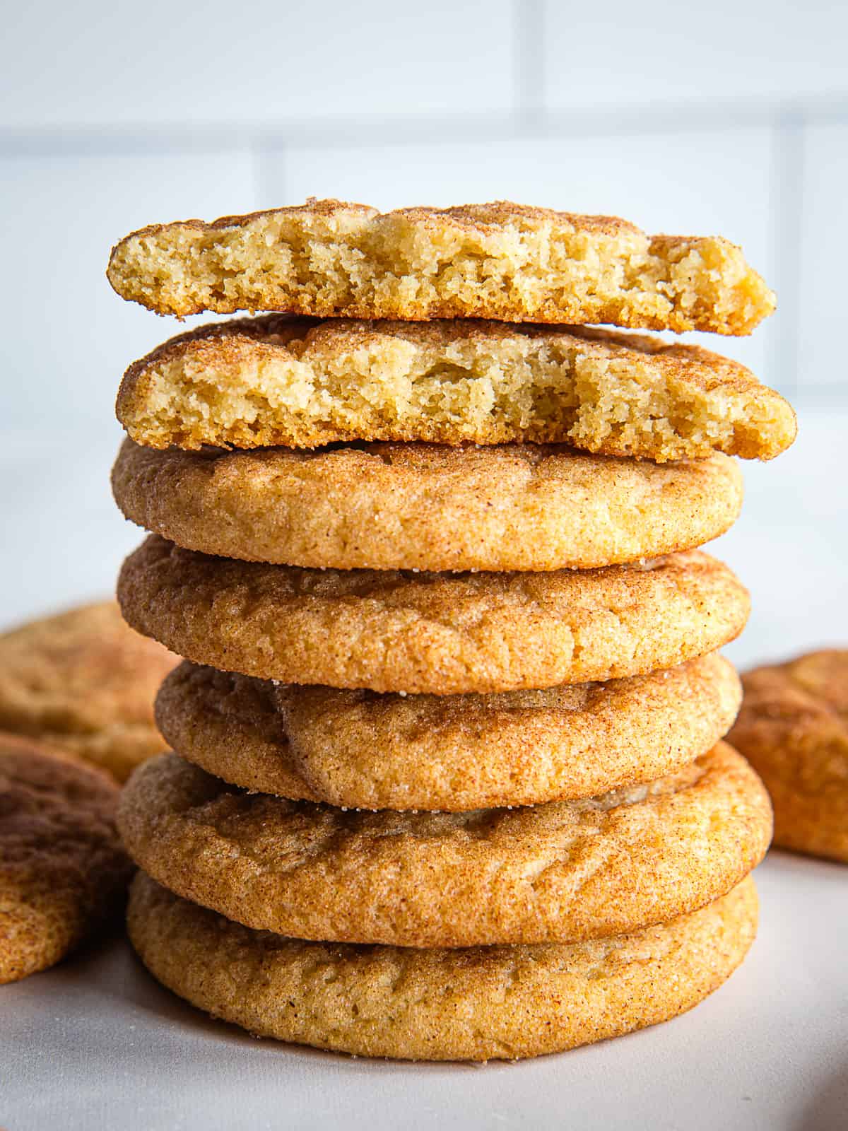 A stack of gluten-free snickerdoodles. The top cookie is broken in half.