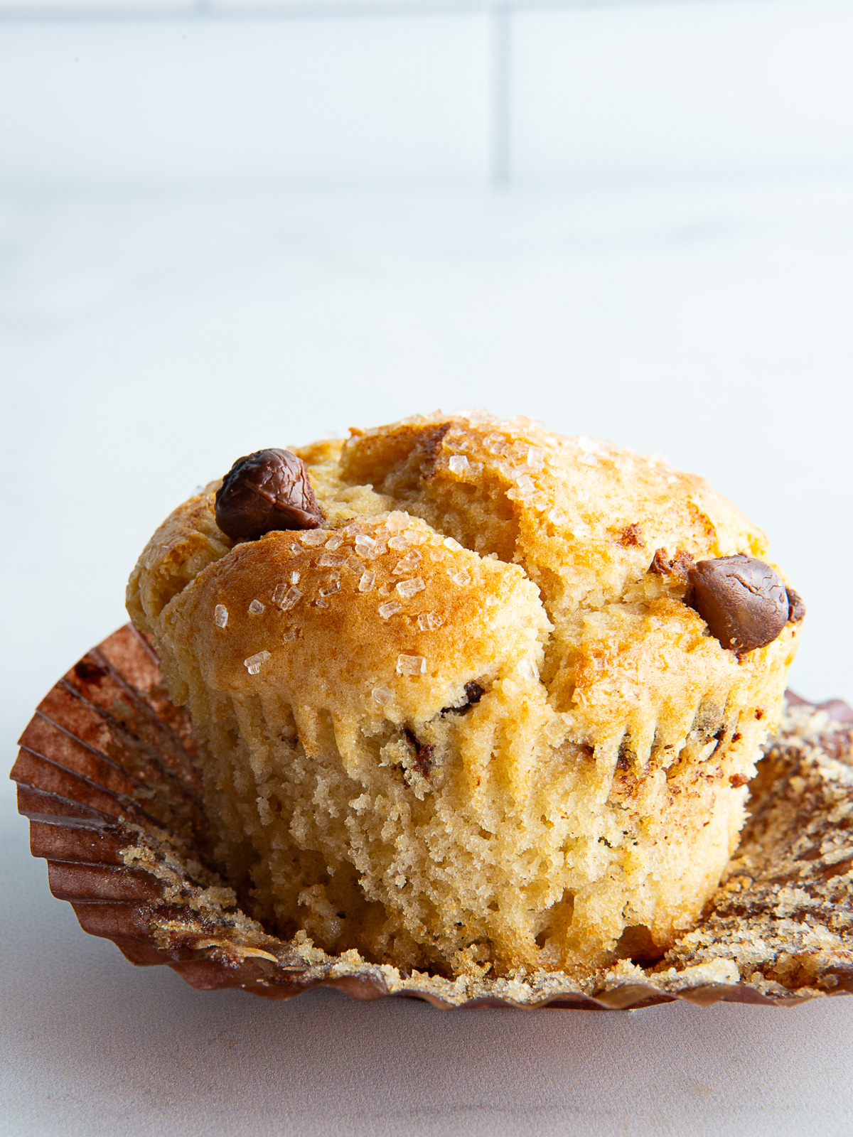 Gluten-free chocolate chip muffin unwrapped on a counter.