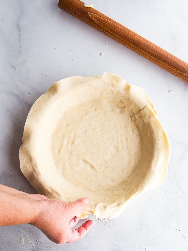 Placing gluten-free pie dough in a pie pan.