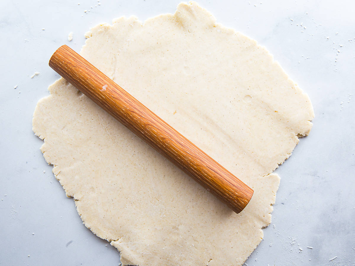Gluten-free pie dough rolled out on the counter with a rolling pin on top of it.