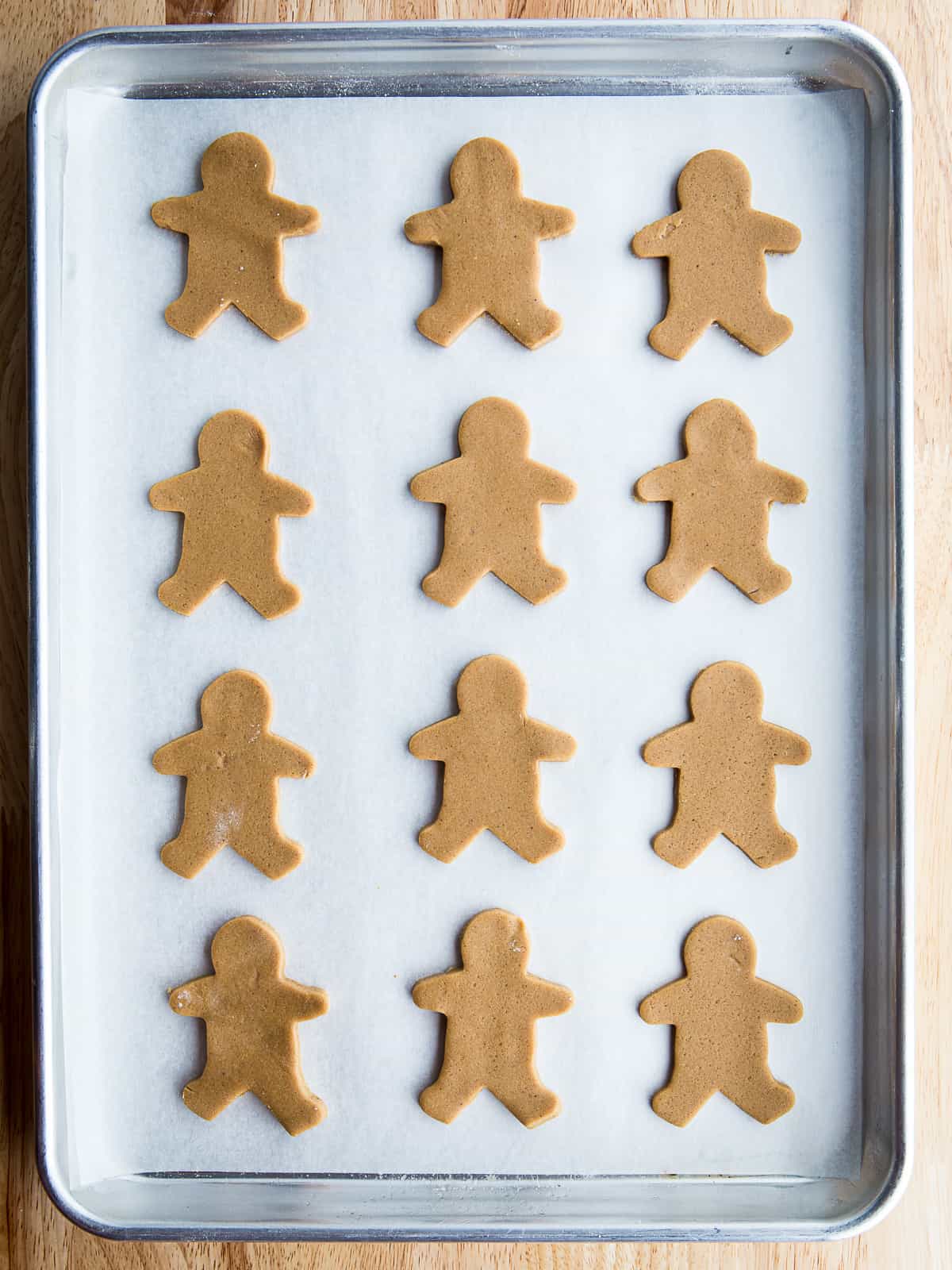 Gluten free gingerbread dough cut into gingerbread men shapes on a baking sheet.