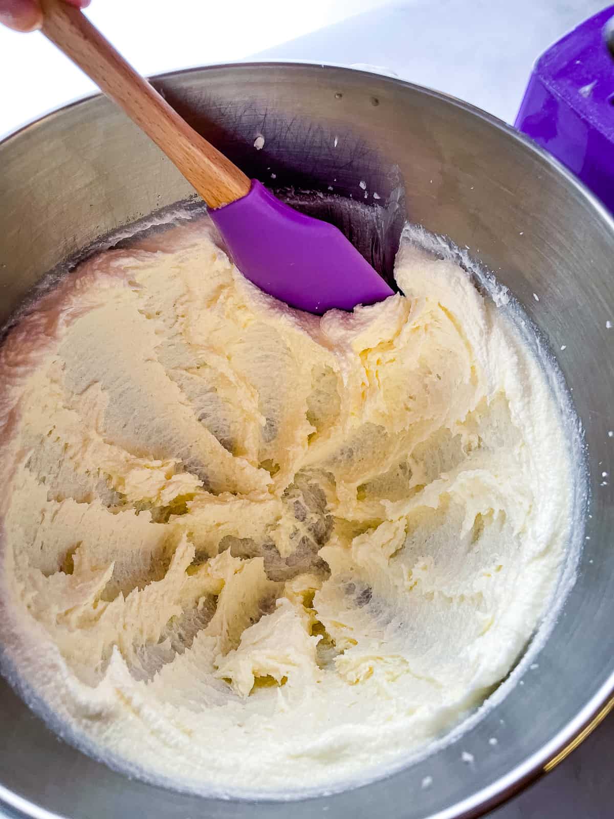 Scraping butter from the side of a mixing bowl for gluten-free pound cake.