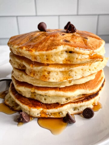 Stack of gluten-free chocolate chip pancakes drizzled with maple syrup.