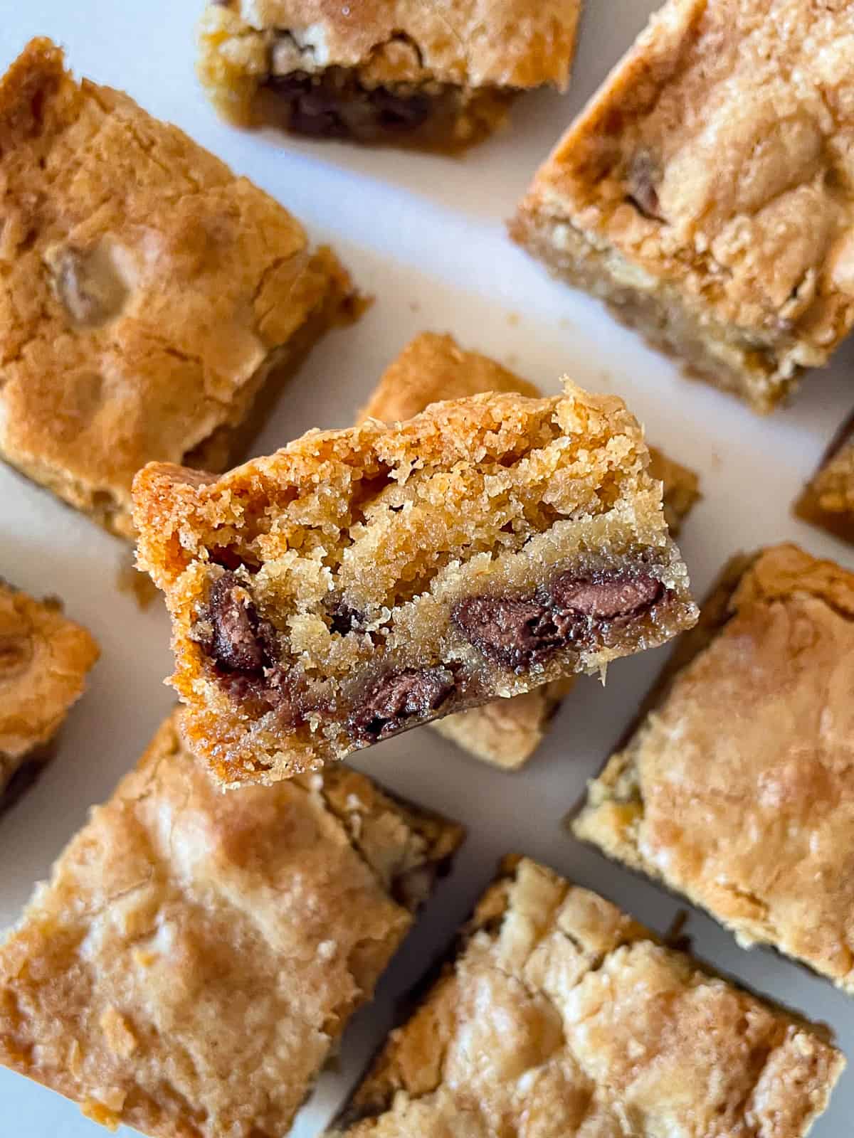 Gluten-free blondies cut into squares. One is stacked on top of the another to show the chocolate chips.