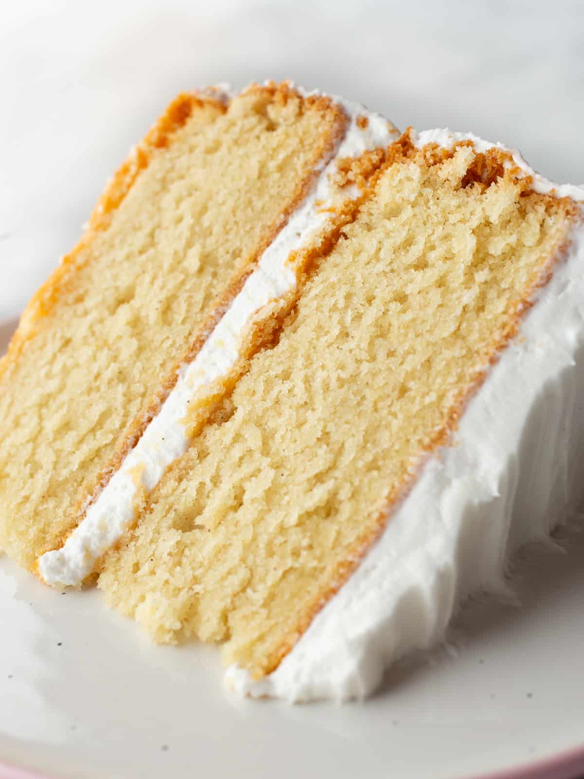 Gluten-free vanilla cake on a plate. The cake is frosted with vanilla buttercream.