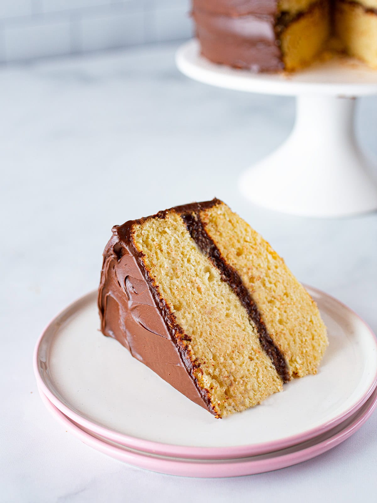 A slice of gluten-free yellow cake with chocolate frosting.