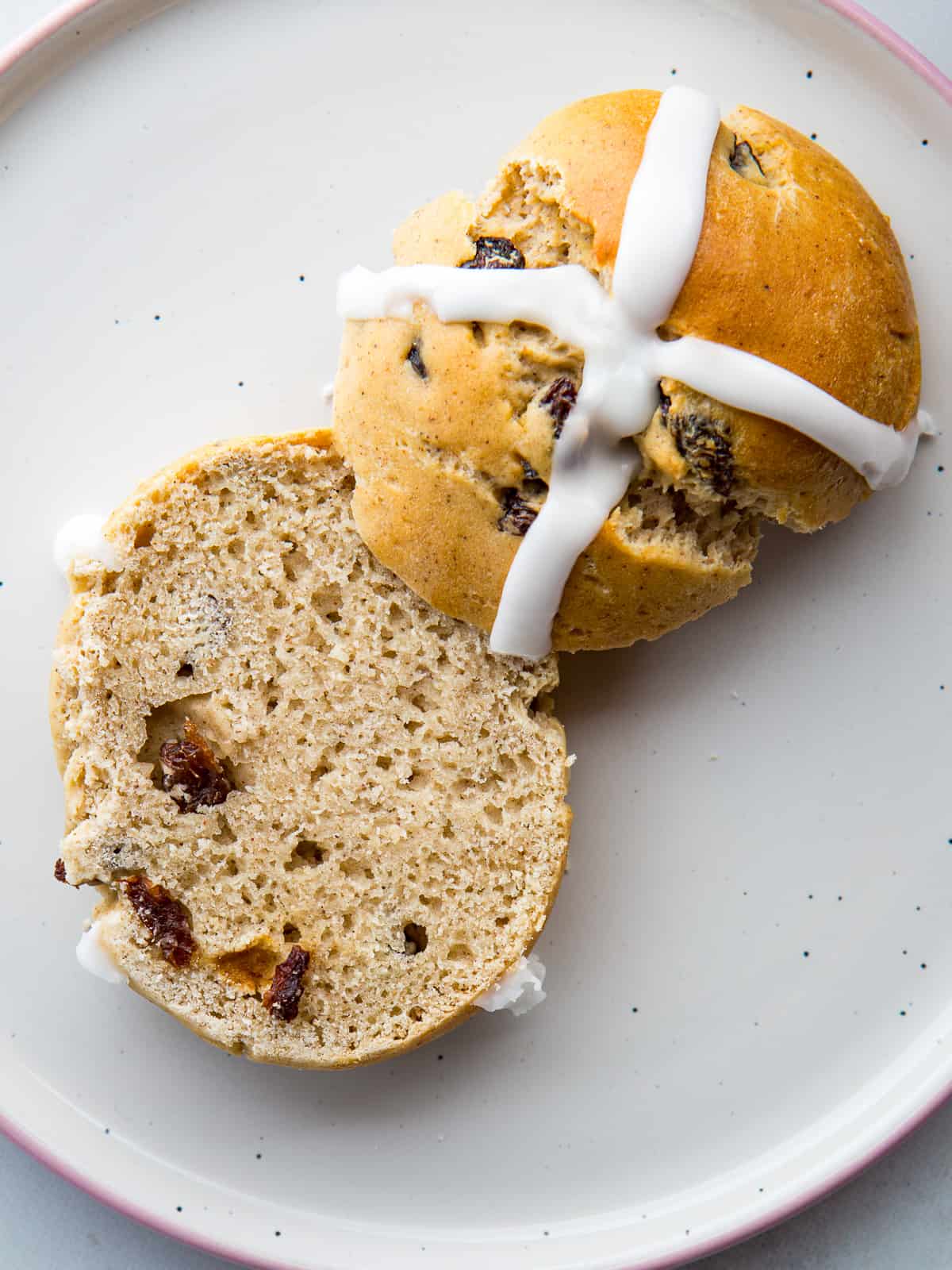 Gluten-free hot cross bun split in half on a plate.