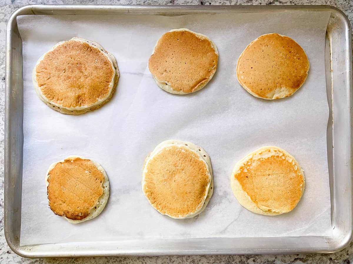 Six gluten-free pancakes on a sheet pan.