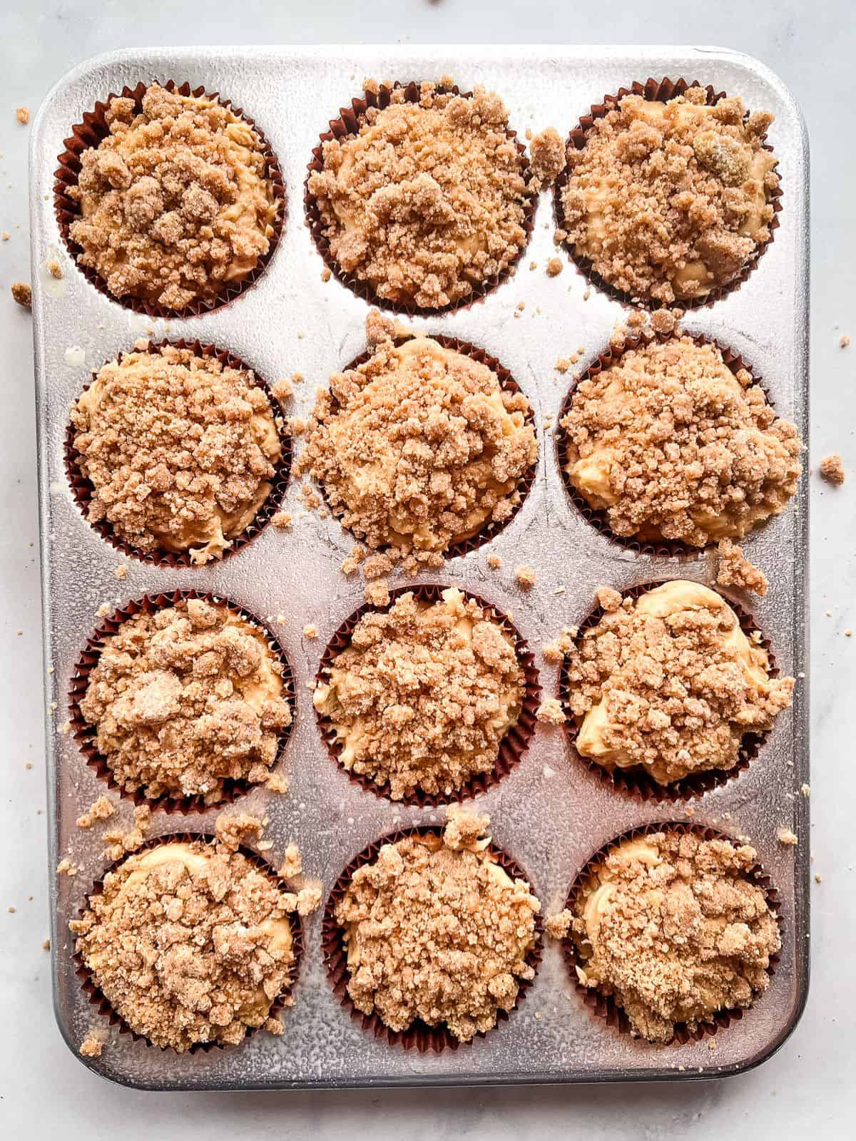 Gluten-free apple muffin batter in pan topped with crumb topping.