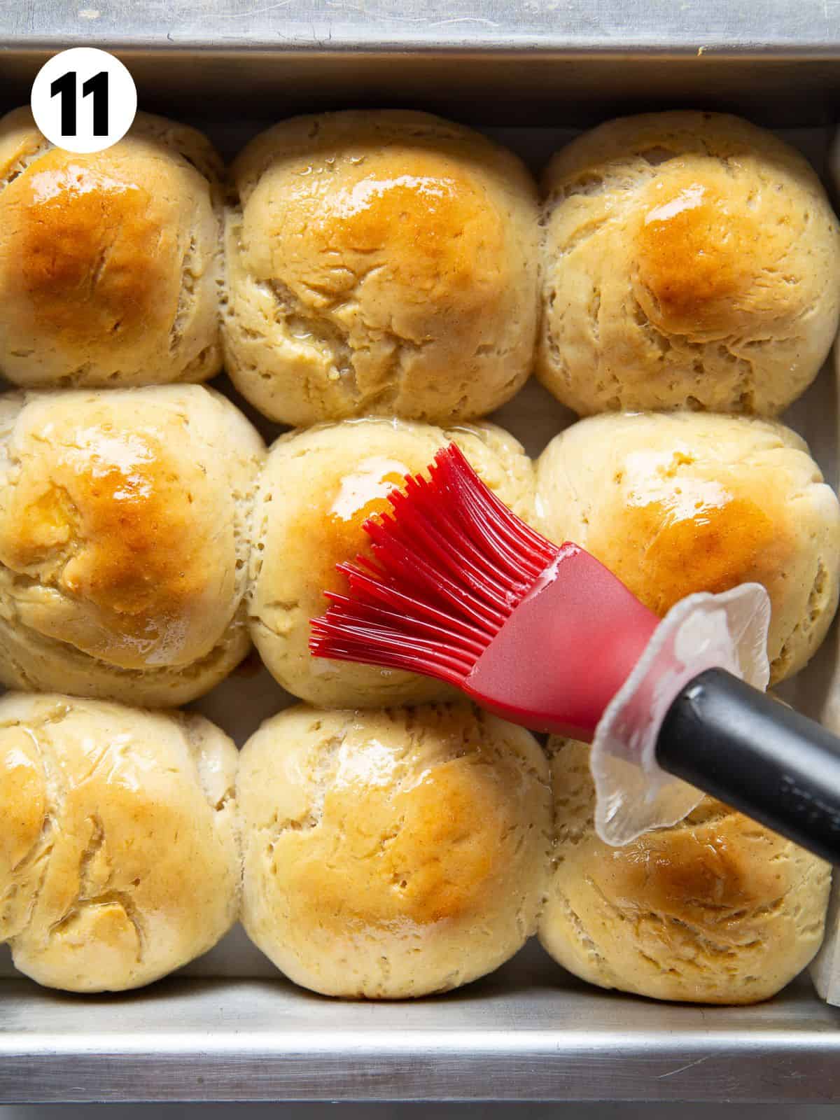 11. Brushing butter onto baked gluten-free soft rolls with a red pastry brush.