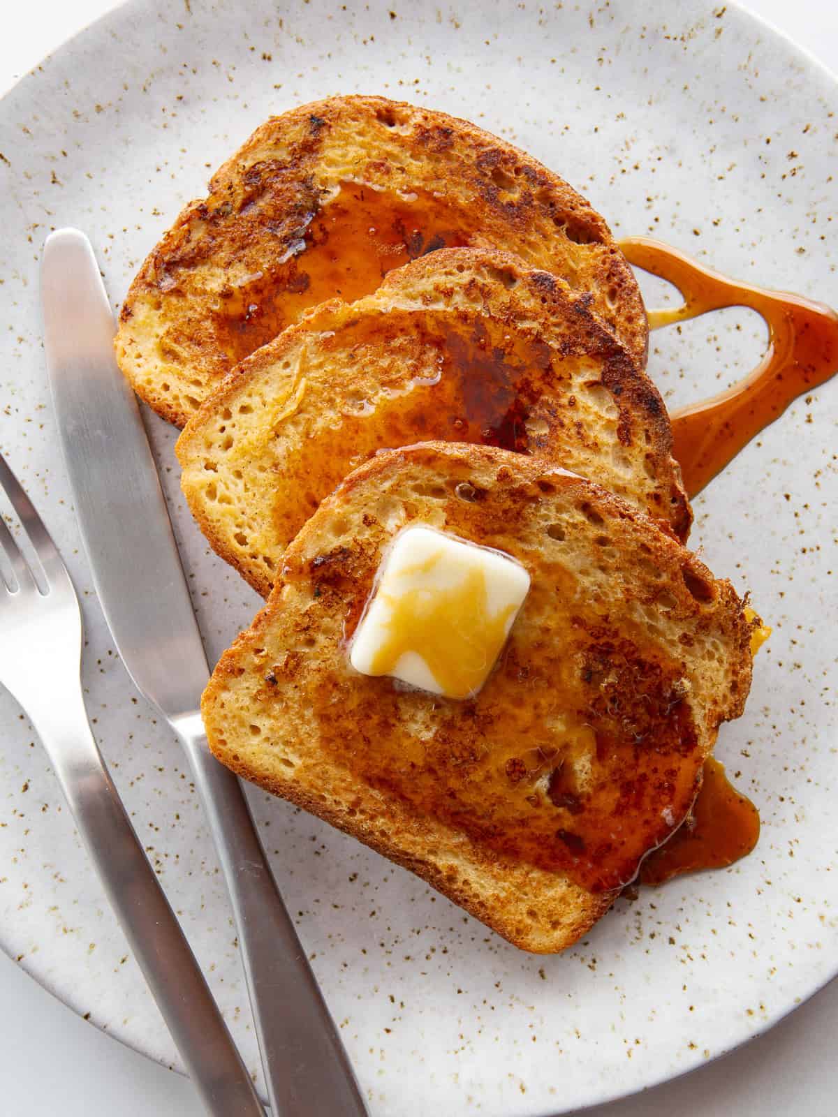 Gluten-free French toast with syrup and butter on a plate.