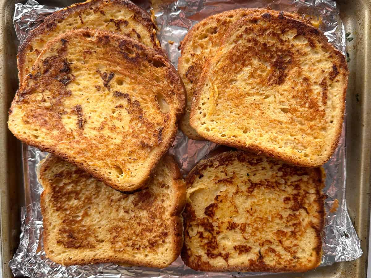 Keeping gluten-free French toast warm on a pan. The slices are stacked on top of each other.