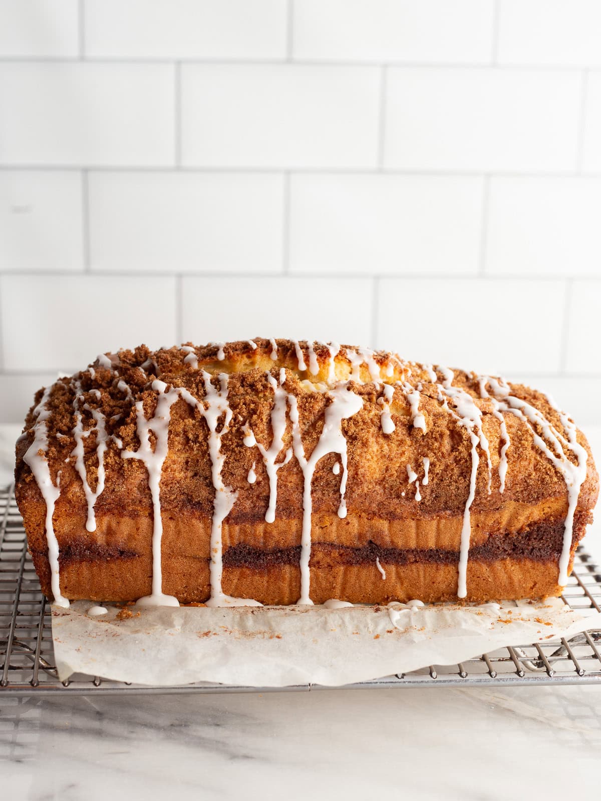 Gluten-free cinnamon swirl bread on a cooling rack after being topped with a vanilla sugar drizzle.