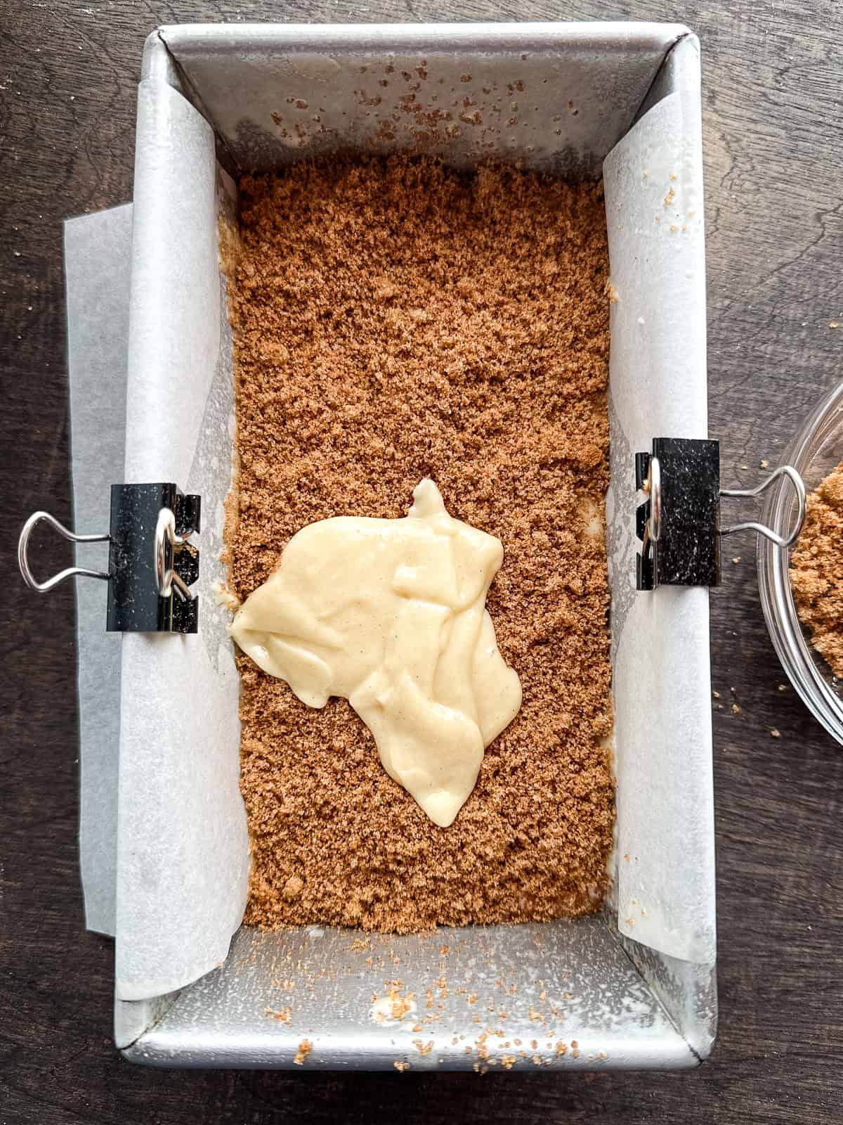 Gluten-free cinnamon swirl batter in a loaf pan. The batter is topped with brown sugar and cinnamon. A spoonful of batter sits on the filling.